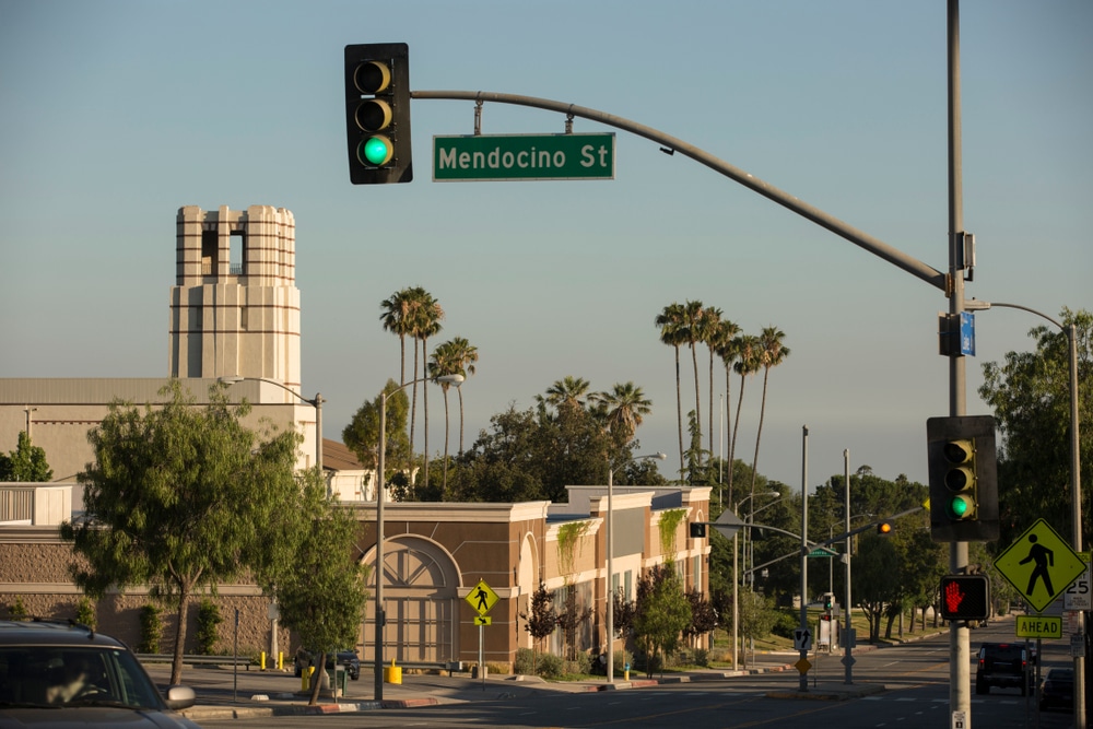 Quiet suburban street with mountain backdrop and mid-century architecture.